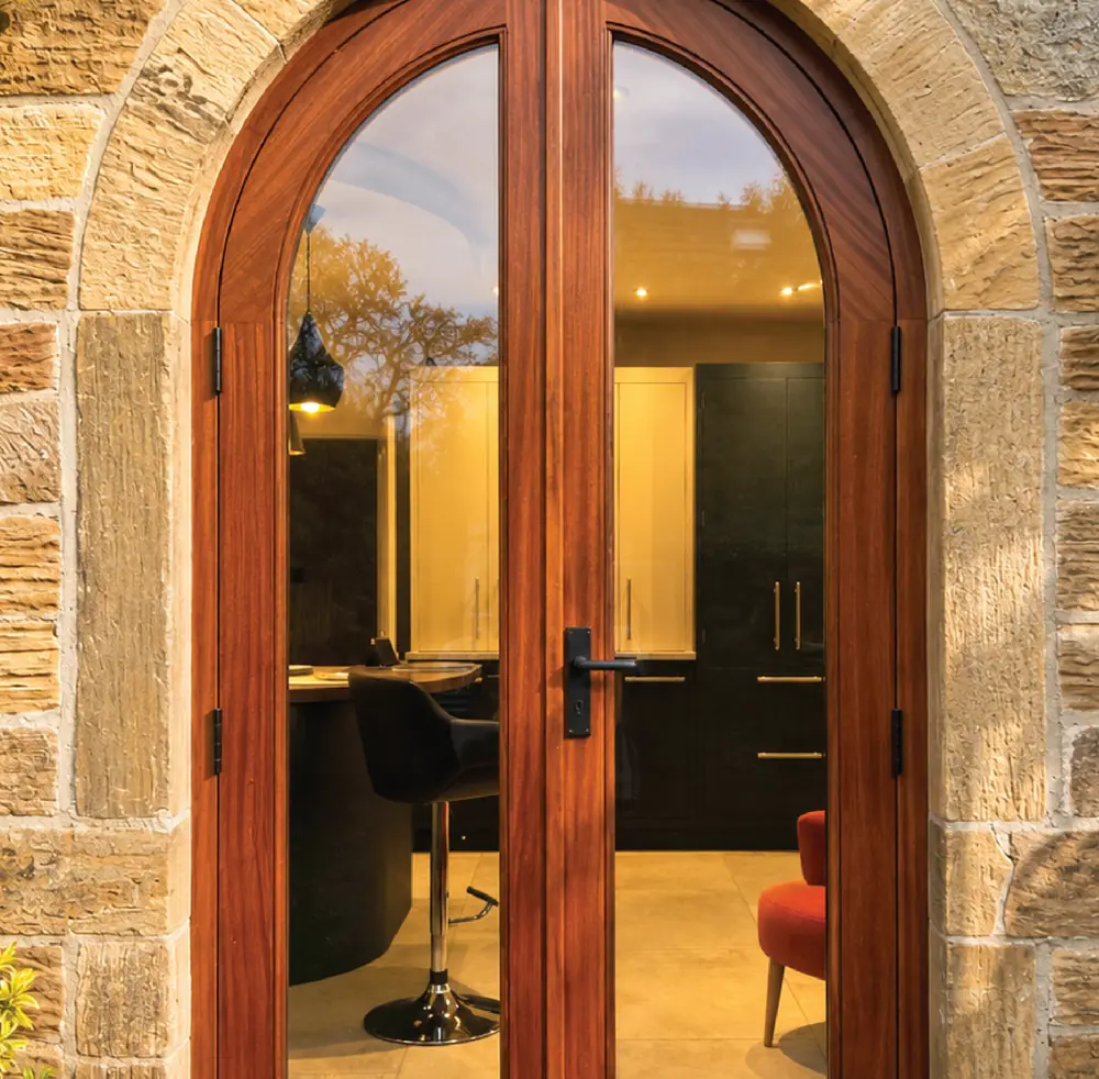 Arched hardwood double doors in a stone opening, looking through to a fitted interior