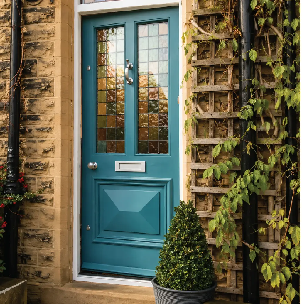 Painted teal front door with stained-glass panels and a letter plate