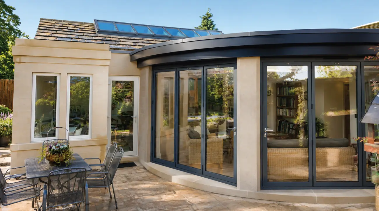 Completed curved extension in dressed stone with dark framed glazing