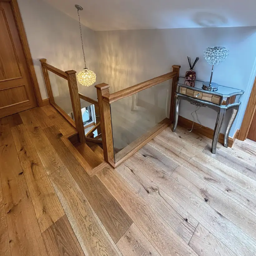 Oak and glass landing balustrade above a wide-board oak floor