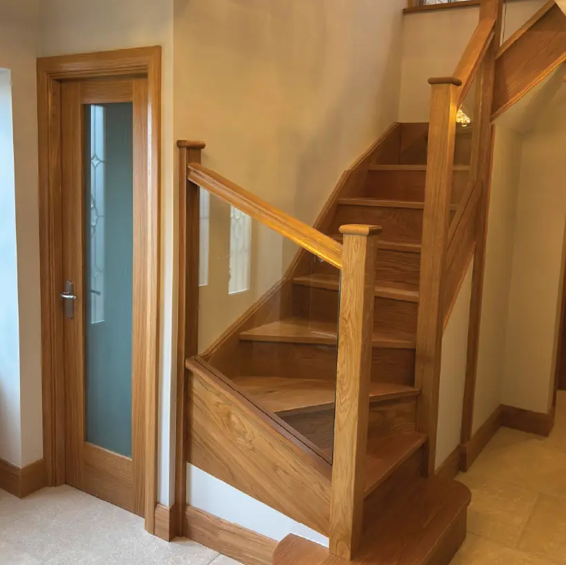 Oak staircase with a glazed balustrade beside an oak glazed door