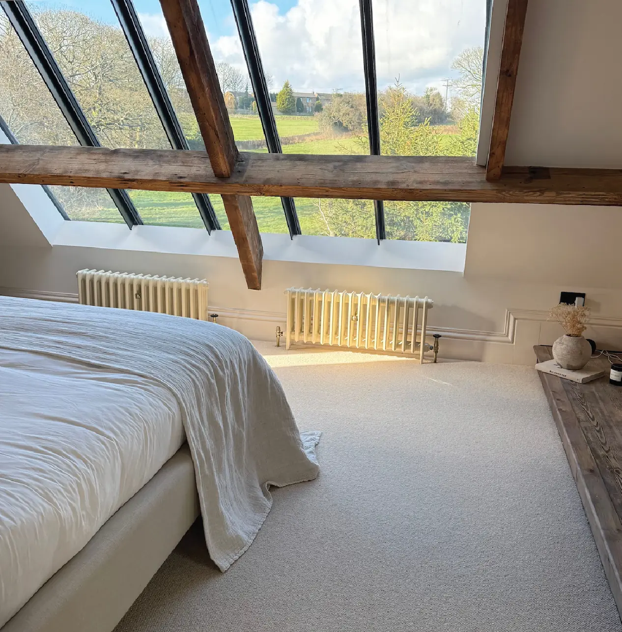 Attic bedroom with exposed beams and new rooflights looking over open fields