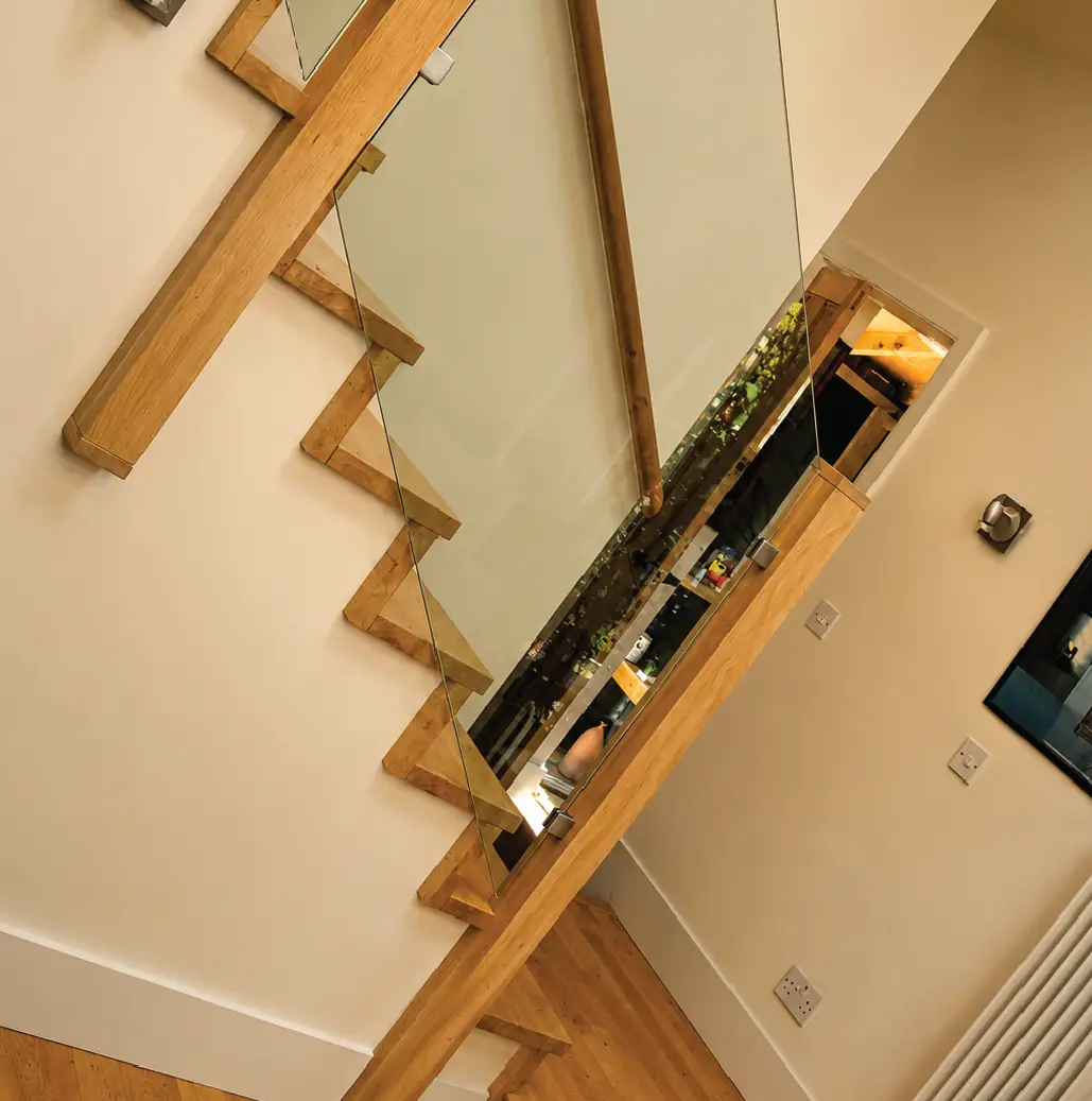 Oak staircase with a glass balustrade, viewed from the landing above